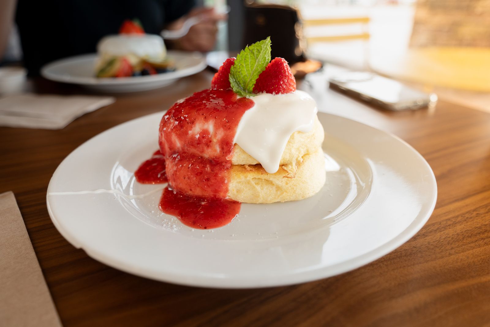 Strawberry shortcake plated on a white dish in warm cafe light